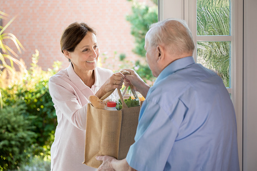 senior receiving groceries from a caregiver