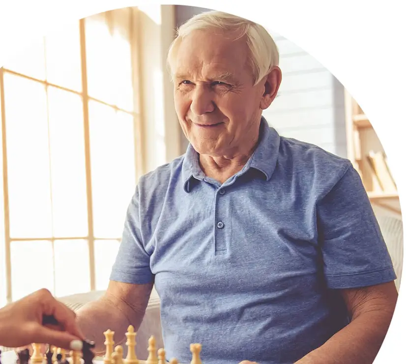 senior man playing chess while smiling
