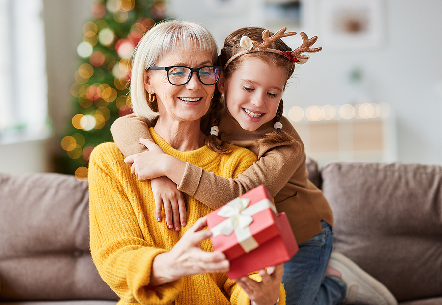 A senior woman opens a gift from her granddaughter.