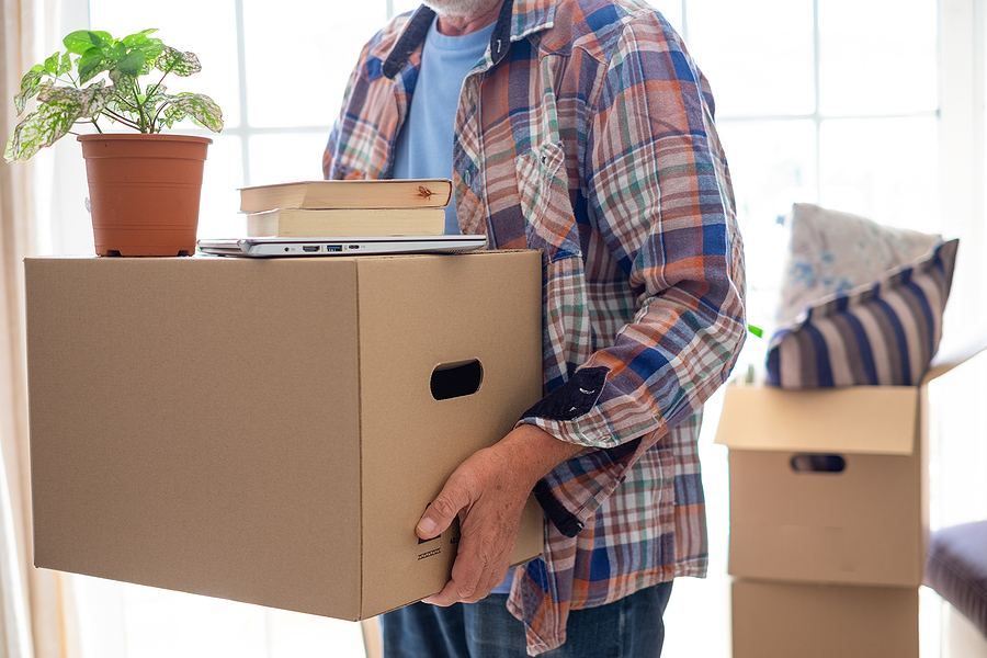 A senior man holding cardboard box moving into new home