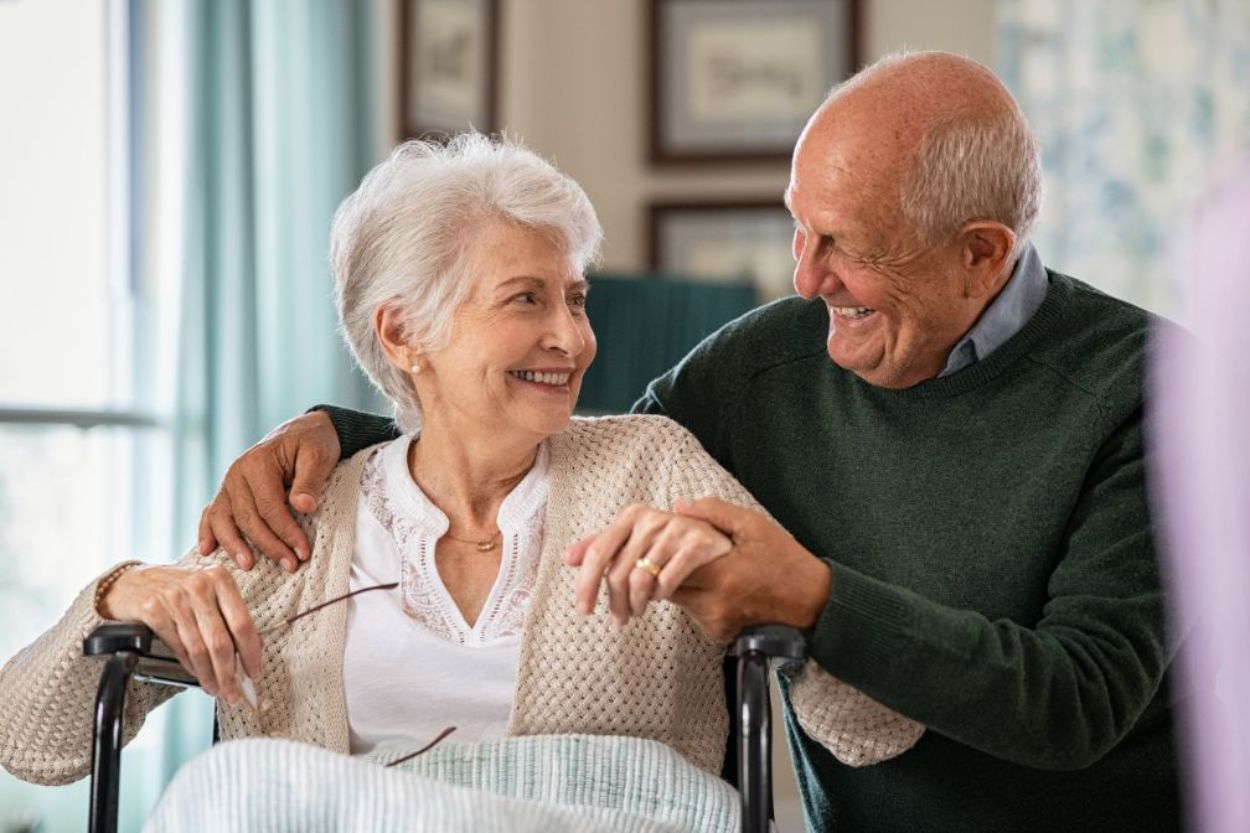 Two older adults smiling lovingly at each other while discussing assisted living.