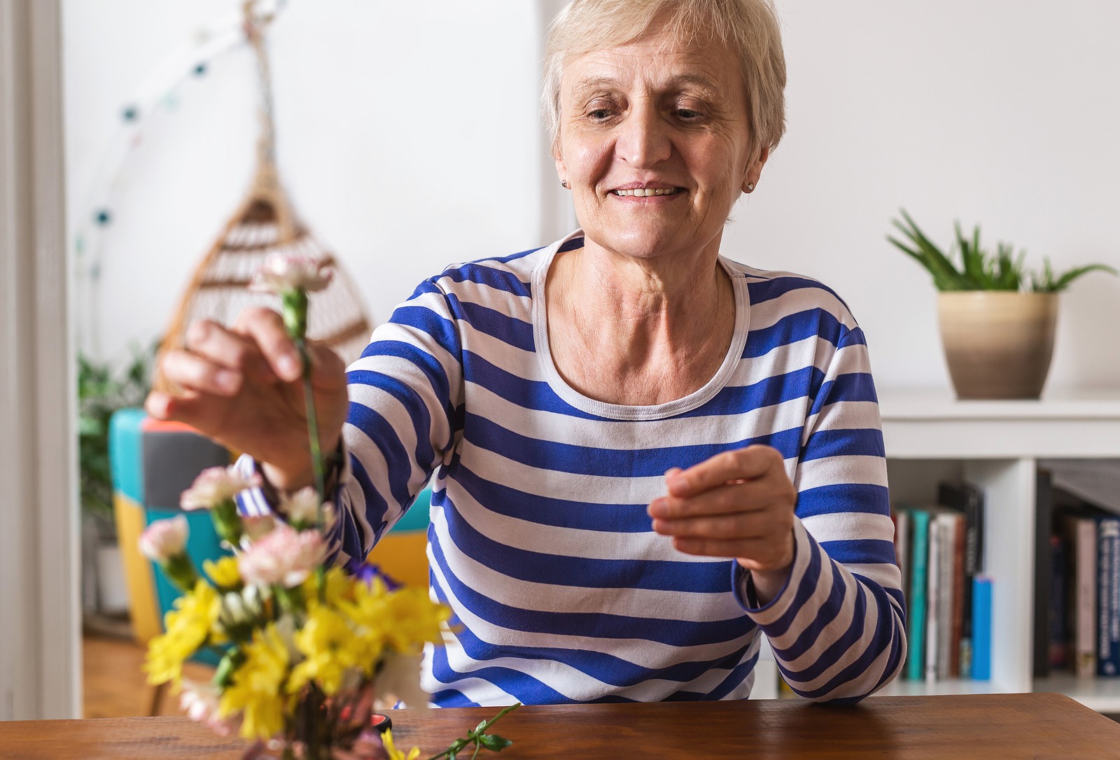 Senior woman decorating her apartment with flowers