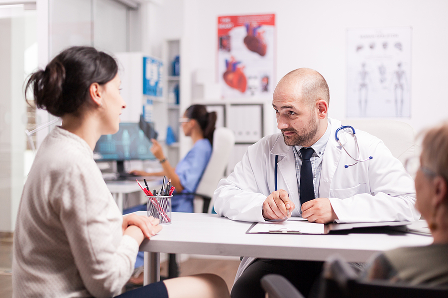 The daughter of a senior patient talking with a doctor