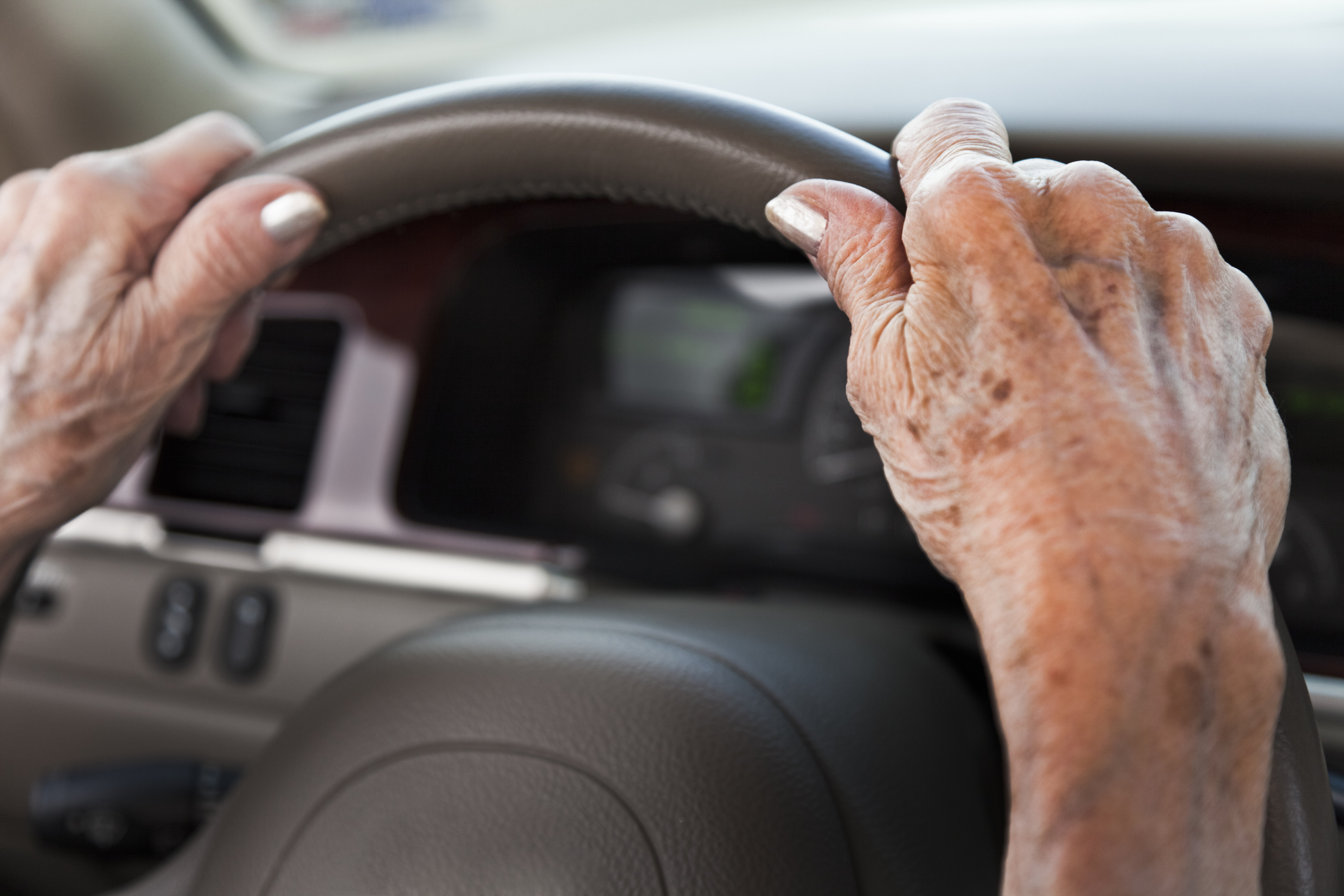 Close-up image of senior hands on a steering wheel