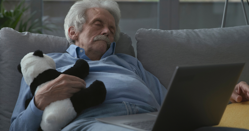 A senior man falls asleep holding a stuffed animal