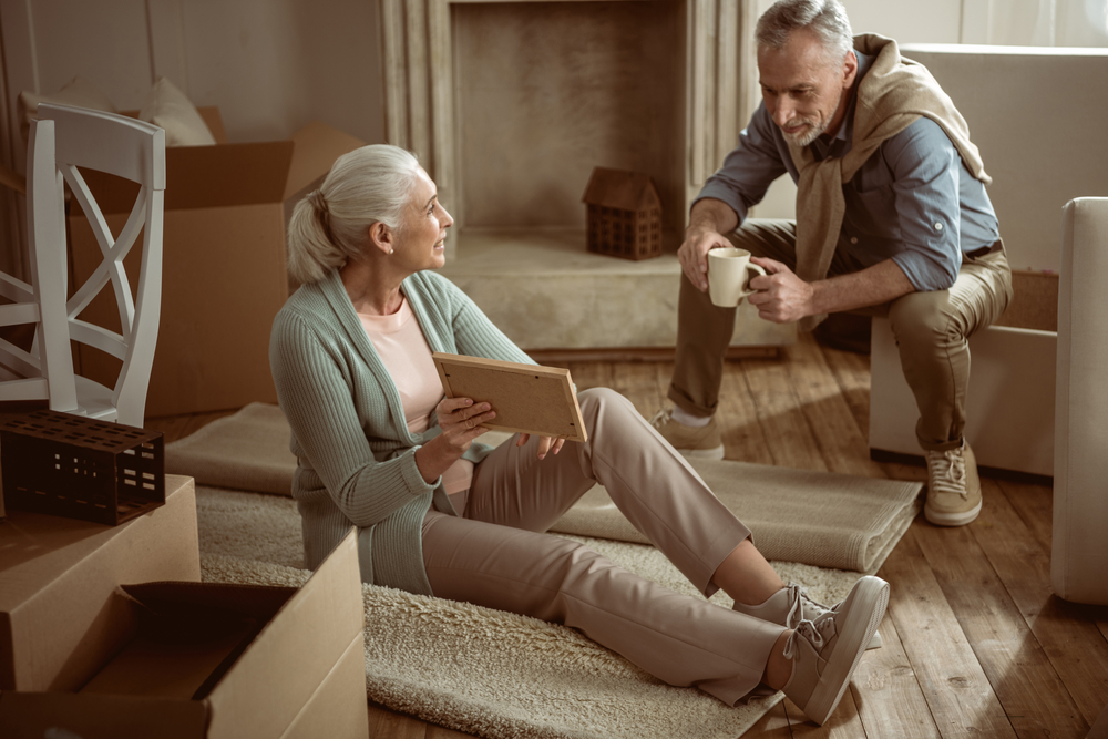 A senior woman and a senior man take a break from packing boxes