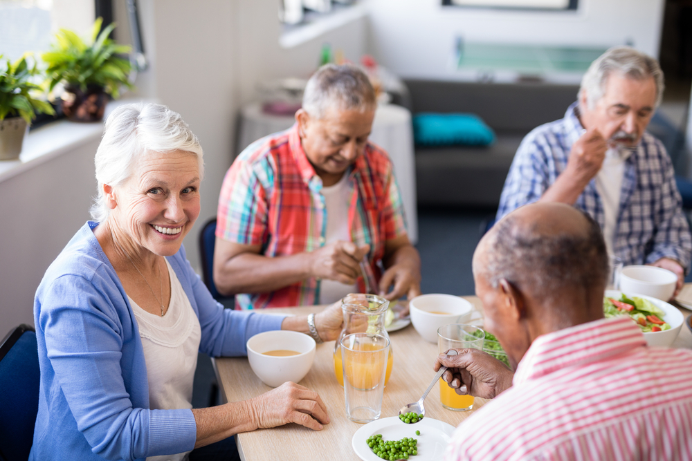 A group of seniors sitting a dining table together eating